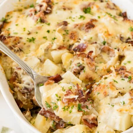 Bacon ranch potatoes in a casserole dish with a serving spoon.