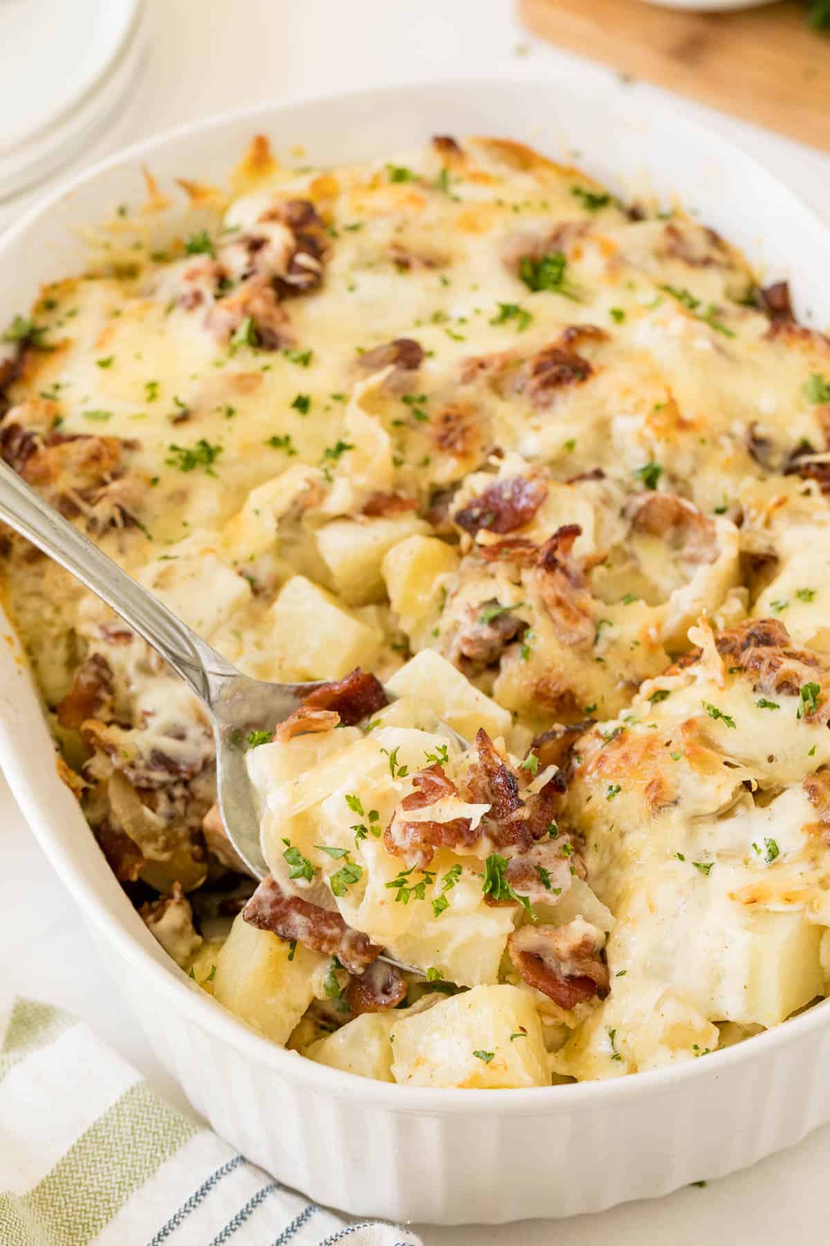 Bacon ranch potatoes in a casserole dish with a serving spoon.