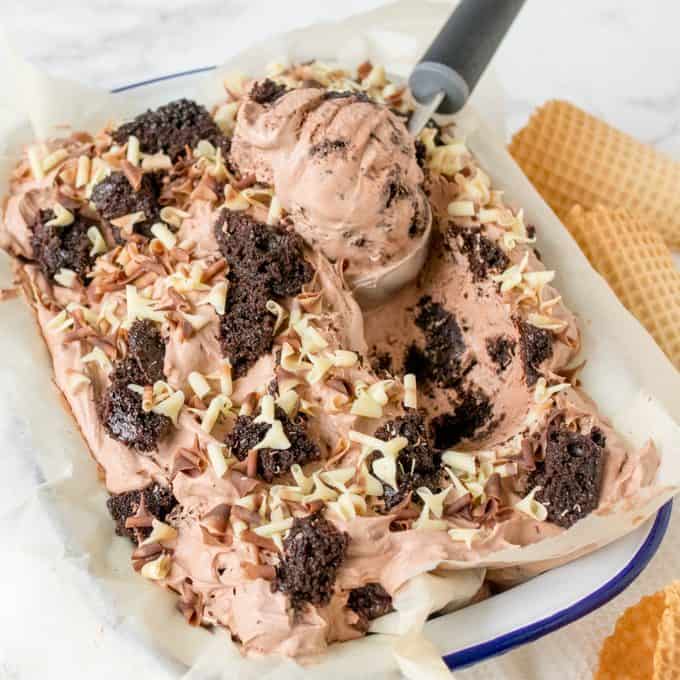 Chocolate cake ice cream in a tub with an ice cream scoop.