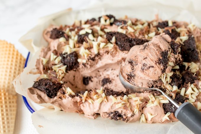 Chocolate cake ice cream in a tub with a scoop.