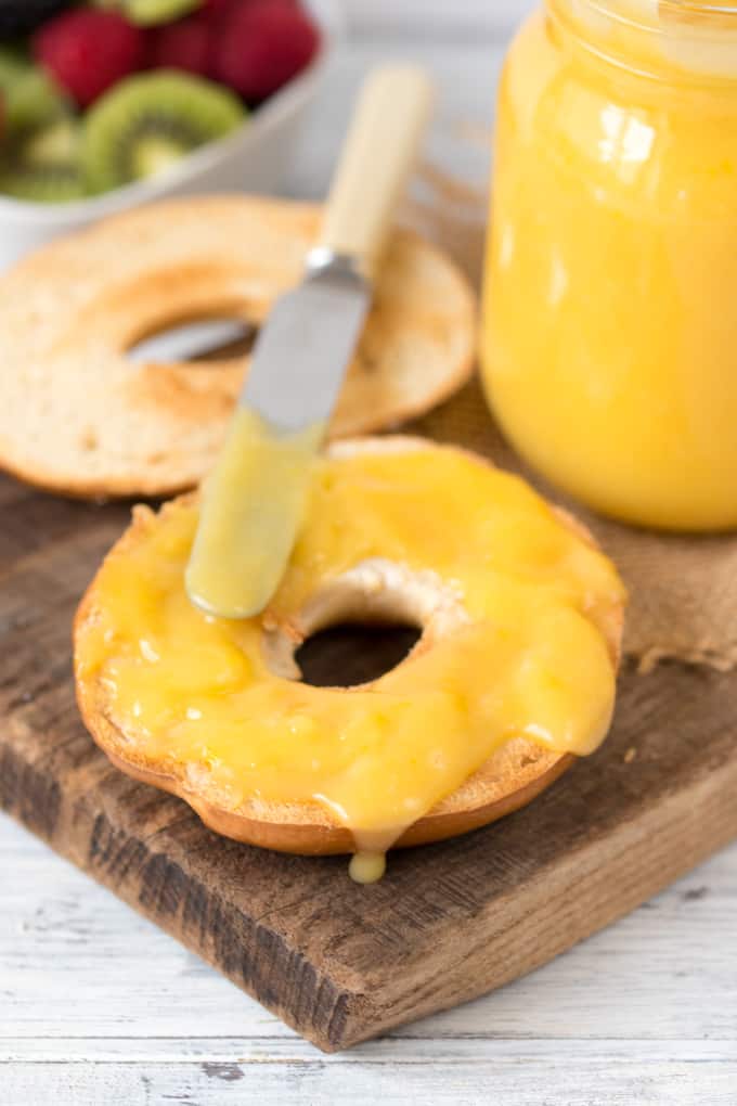 Homemade lemon curd on a bagel with a butter knife.