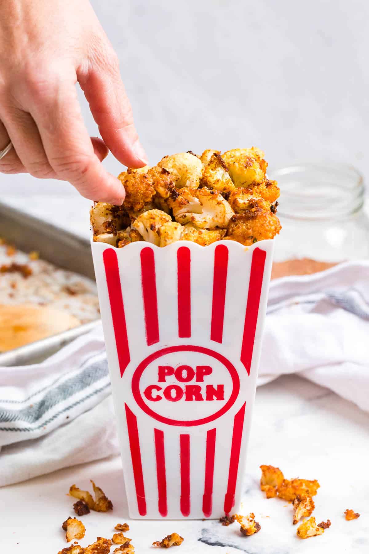 A hand reaching into a container of buffalo popcorn.