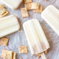 Cereal milk popsicles laying flat on parchment paper.