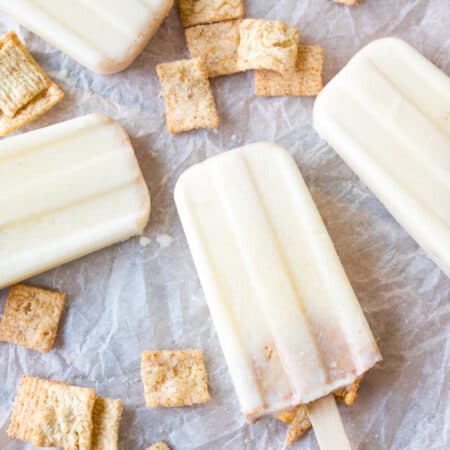 Cereal milk popsicles laying flat on parchment paper.