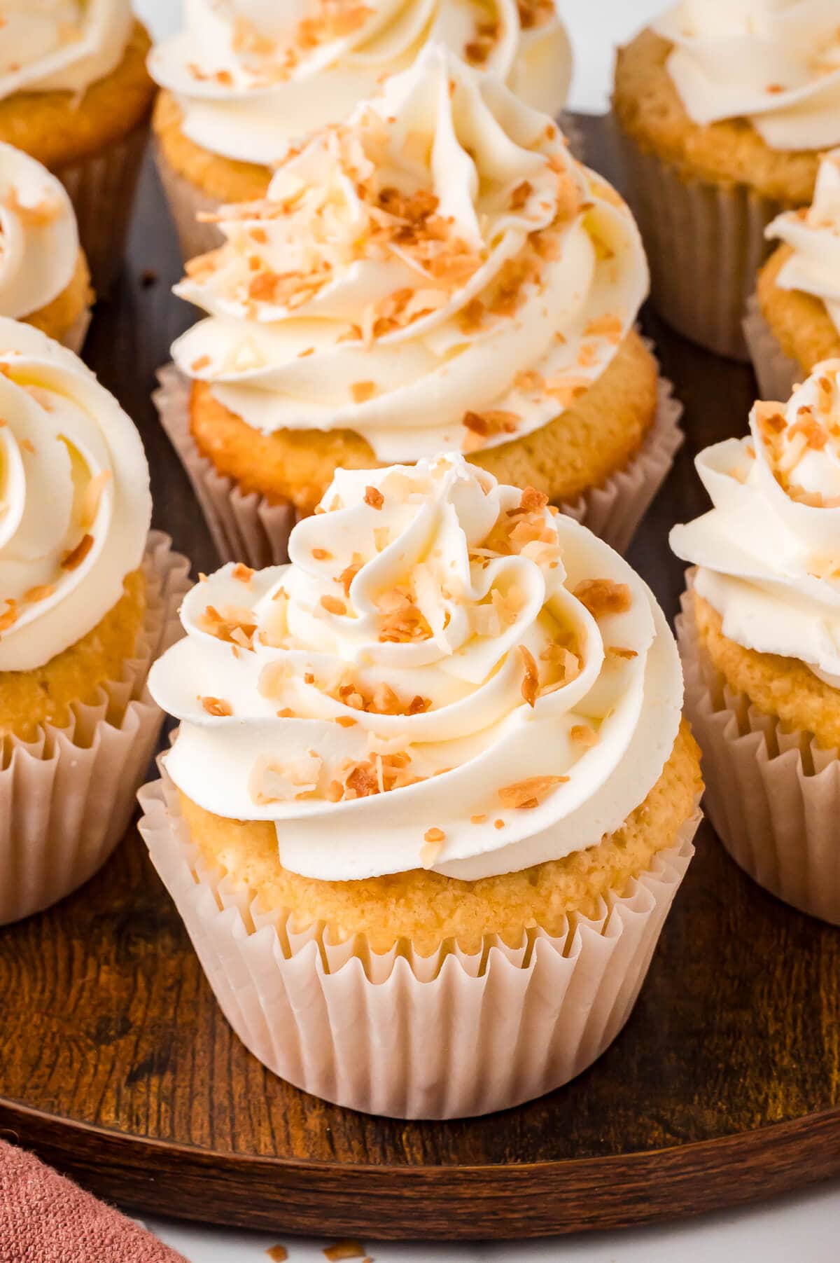 Coconut cream pie cupcakes on a wooden surface.