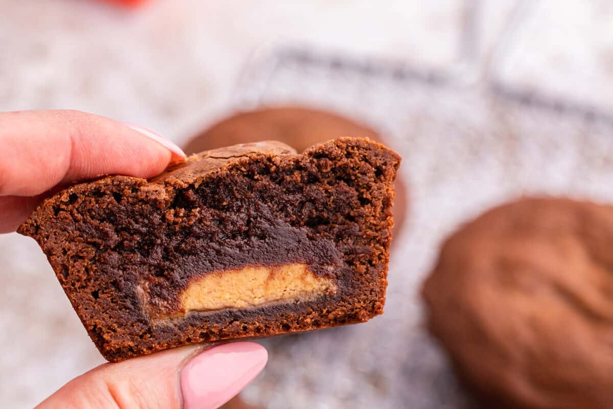 A hand holding a Reese's stuffed brownies cut in half.