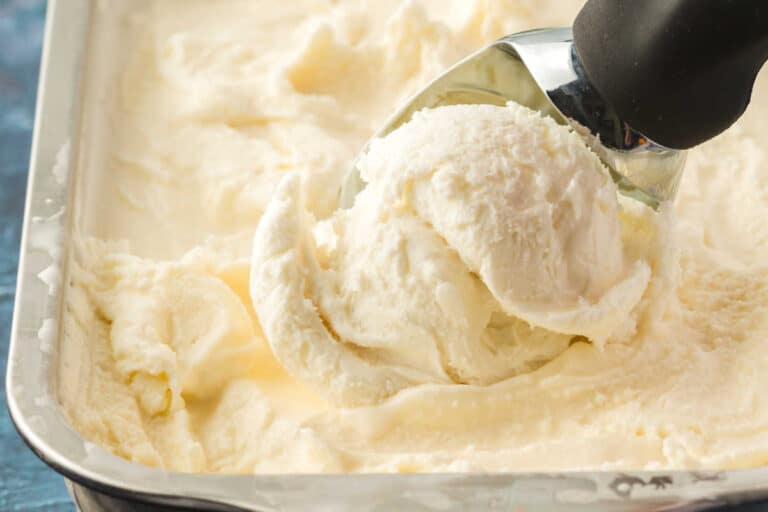 A tub of vanilla ice cream with an ice cream scoop.