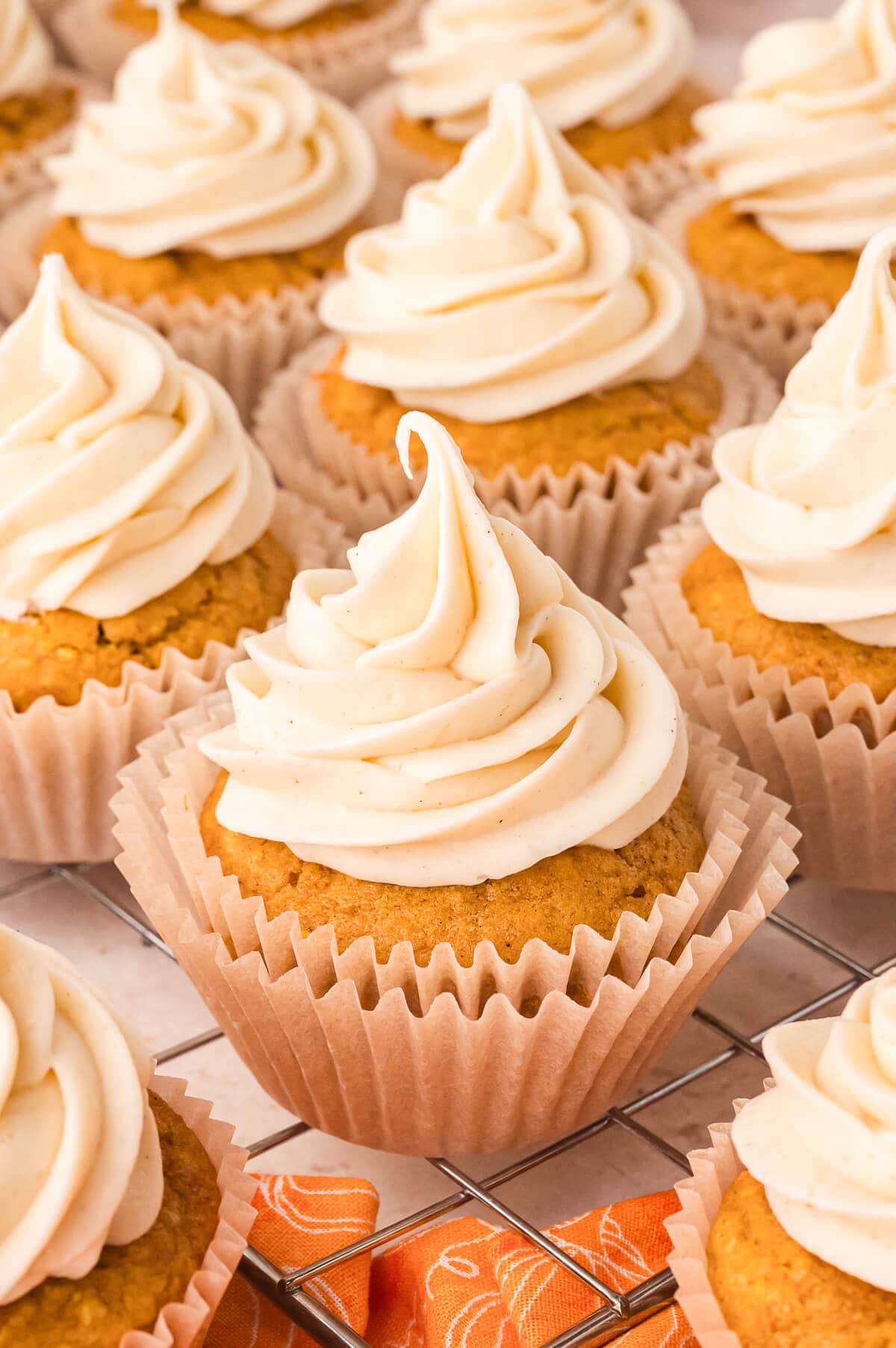 A group of pumpkin pie cupcakes on a wire rack.