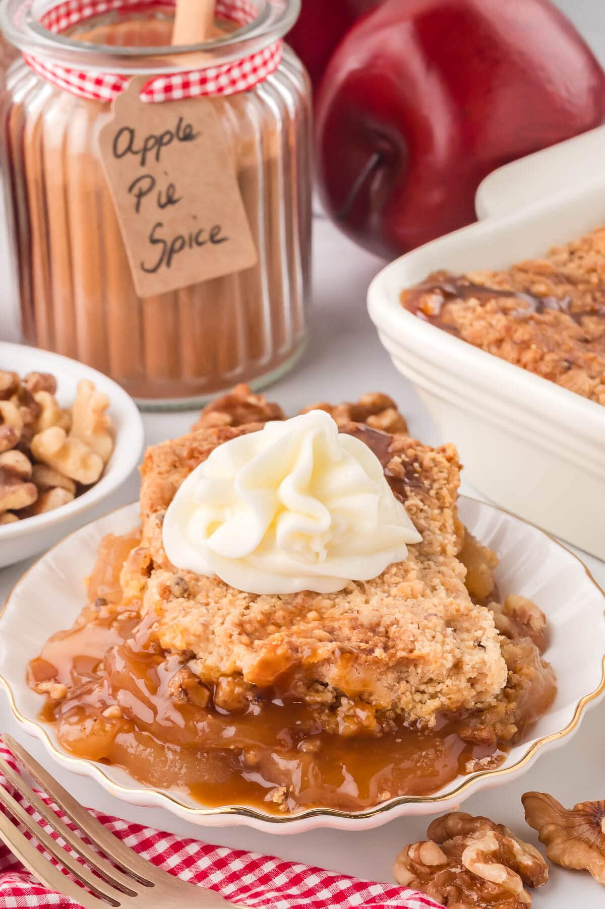 A piece of apple dump cake topped with whipped cream in a white bowl.