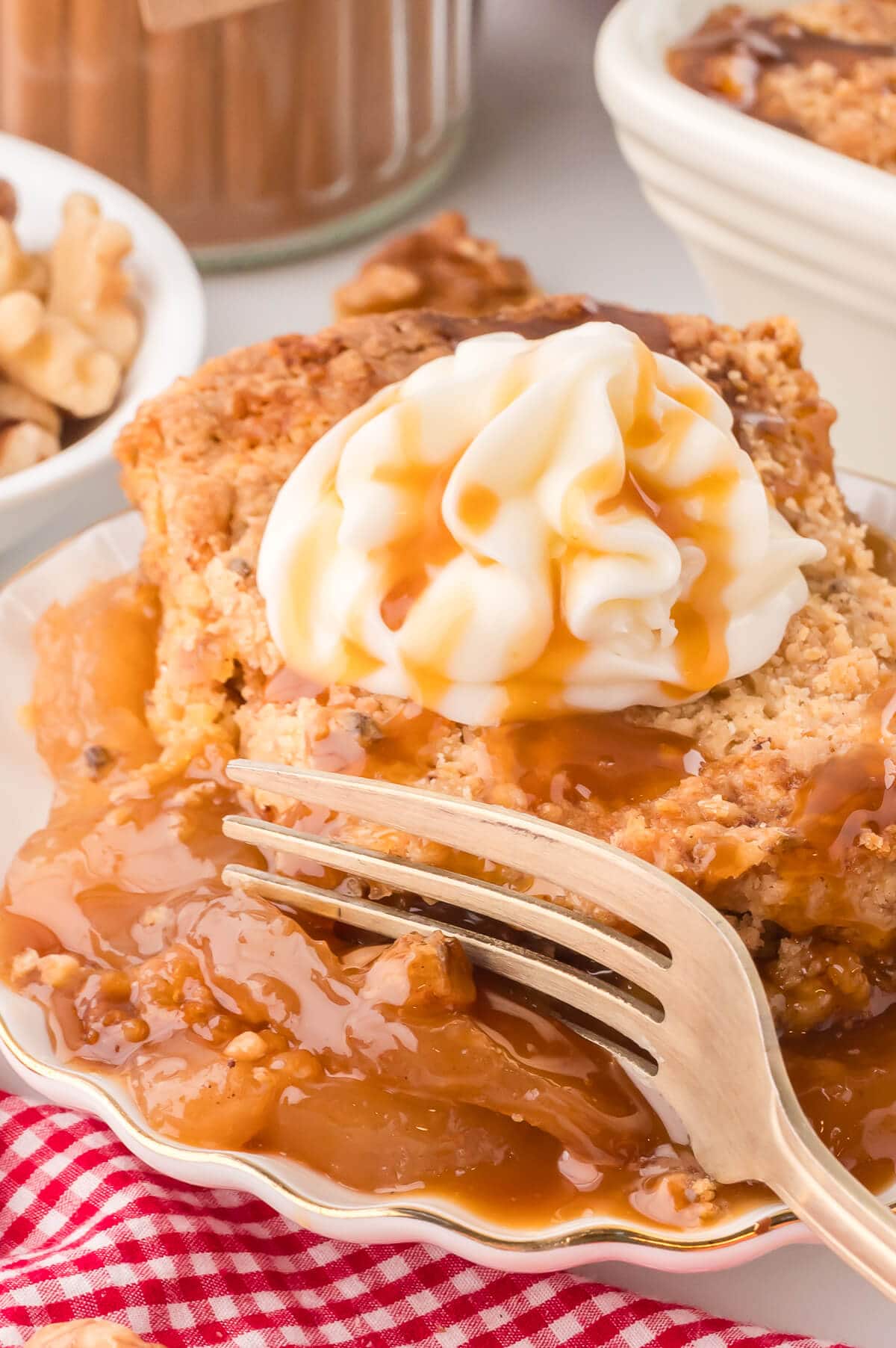 The cake on a plate topped with whipped cream and caramel and a fork digging into it.