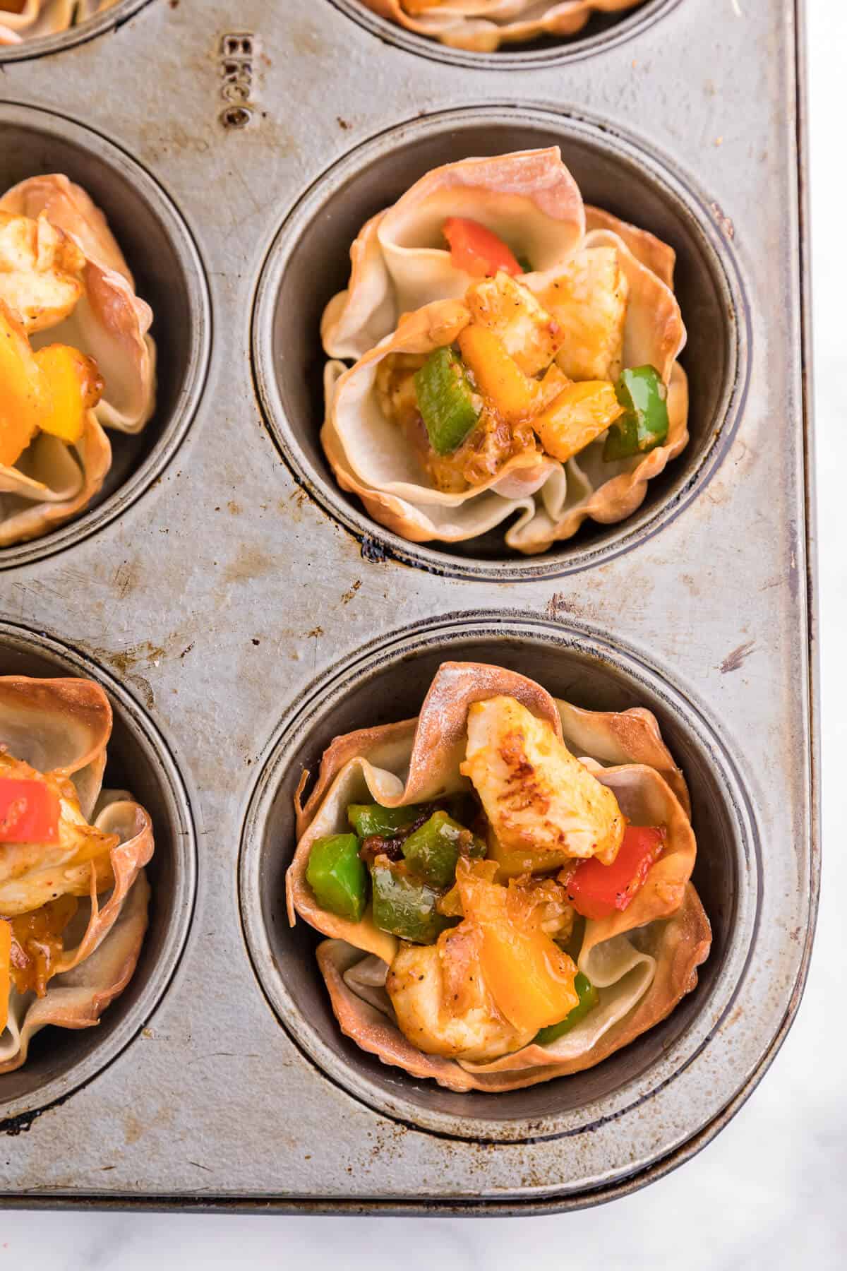 Chicken Fajita Wonton Cups - A little East, a little West. These appetizer cups are perfect for entertaining with a festive Mexican filling in a crunchy wonton.