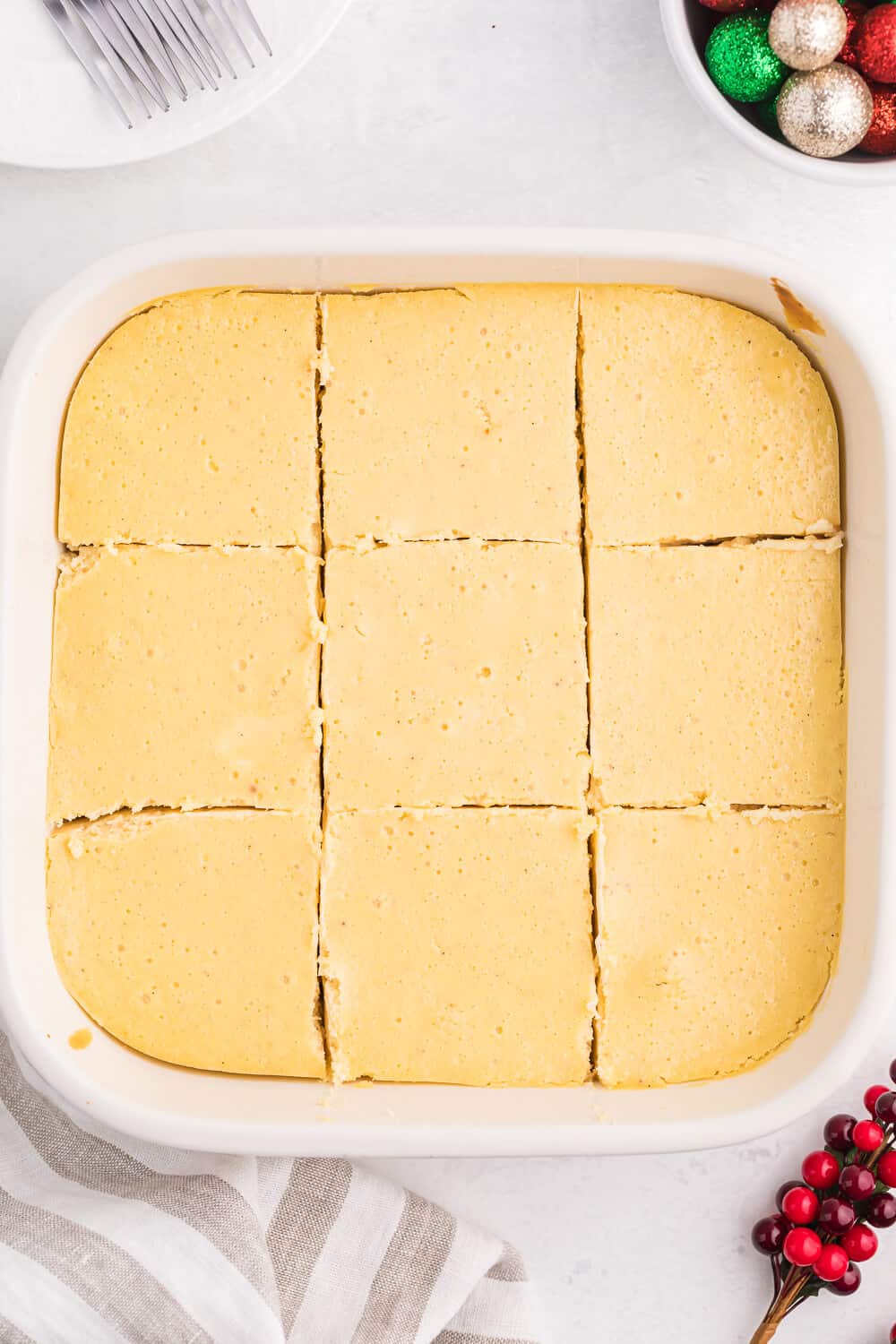 Eggnog cheesecake bars in a casserole pan with cut slices into the squares.