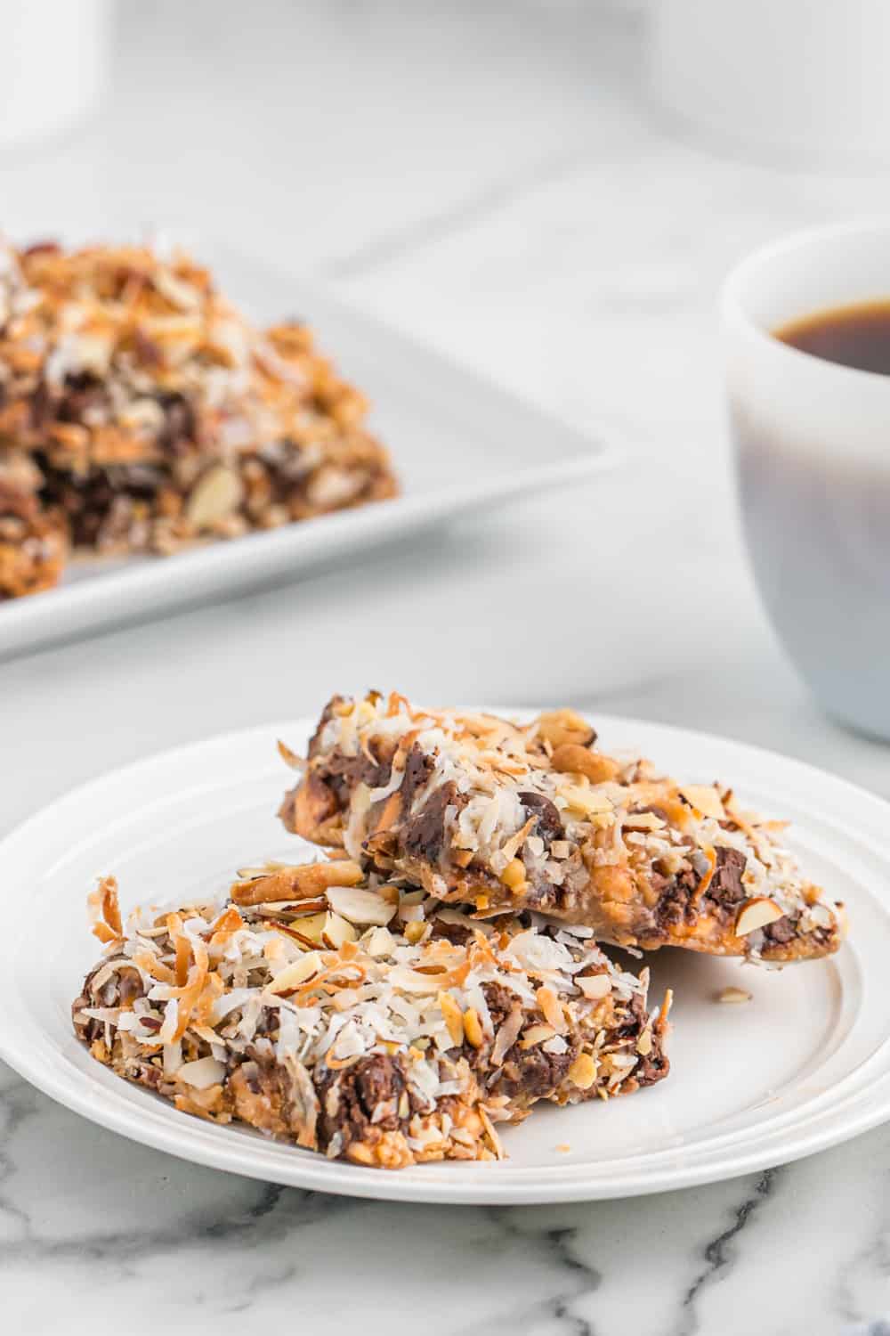 two magic cookie bars on a white plate