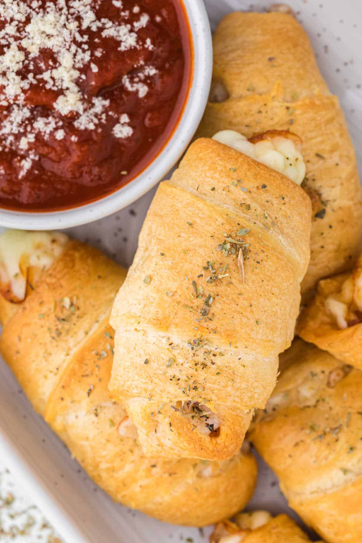 Pizza rolls on a platter with pizza sauce.