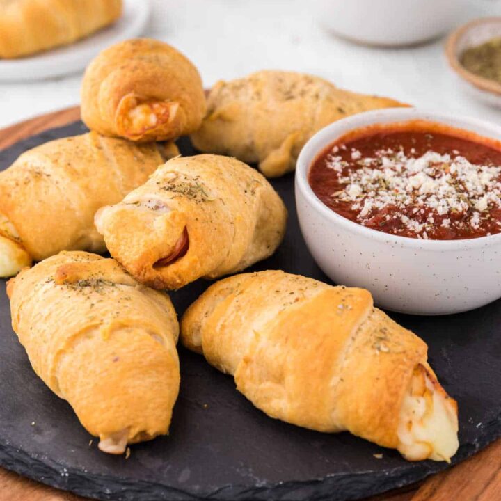 Pizza rolls on a black round slate.