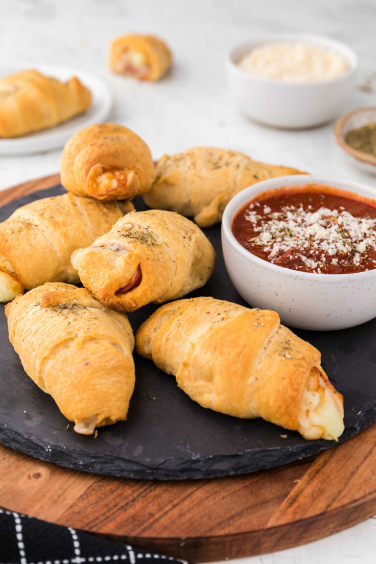 Pizza rolls on a black round slate.