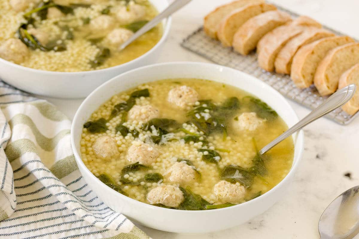 Italian meatball soup in a bowl with a spoon.