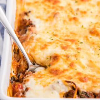 spaghetti bake in a white casserole pan with a serving spoon