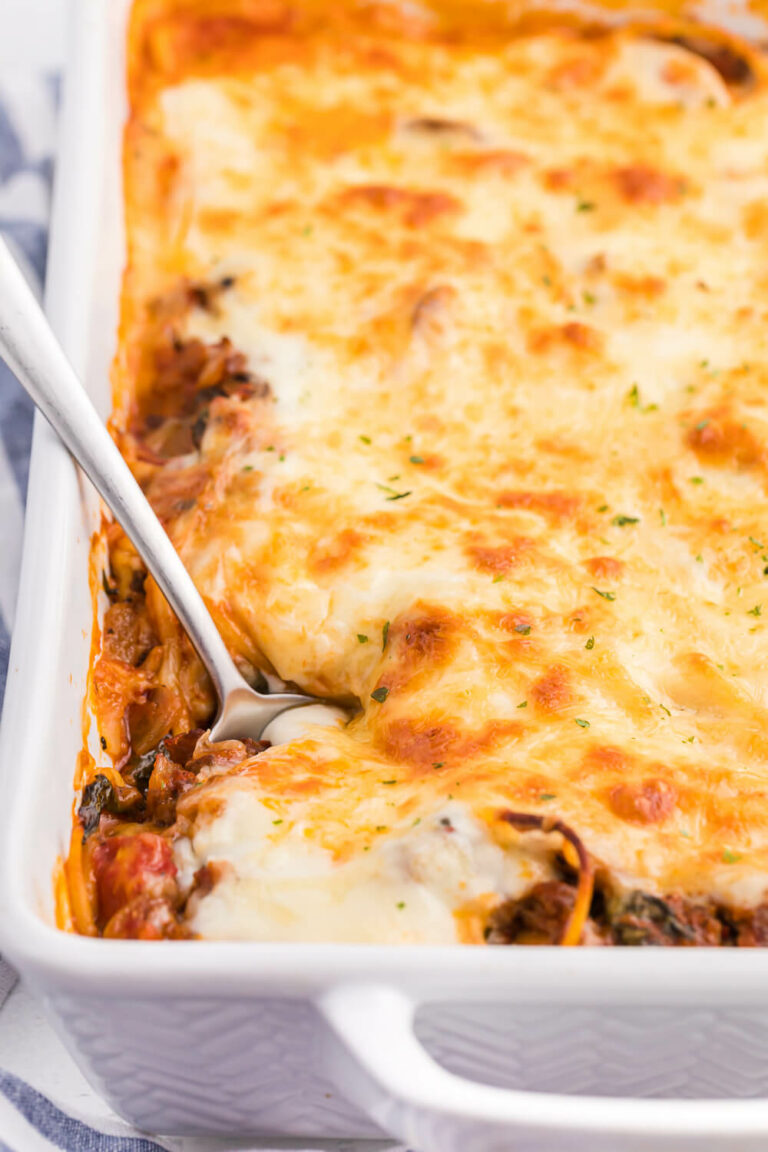 spaghetti bake in a white casserole pan with a serving spoon