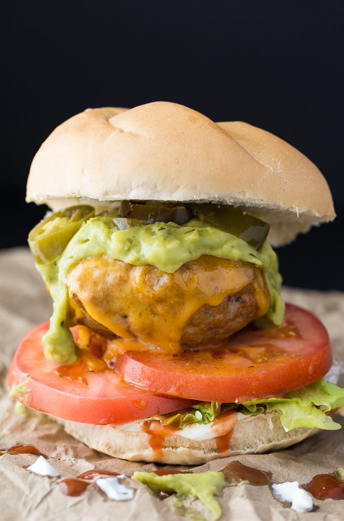 Taco Chicken Burgers - Switch it up for Mexican night! These healthier oven-baked chicken burgers are made with taco seasoning and topped with guacamole, jalapenos, and of course, cheese.