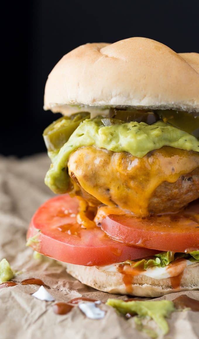 Taco Chicken Burgers - Switch it up for Mexican night! These healthier oven-baked chicken burgers are made with taco seasoning and topped with guacamole, jalapenos, and of course, cheese.