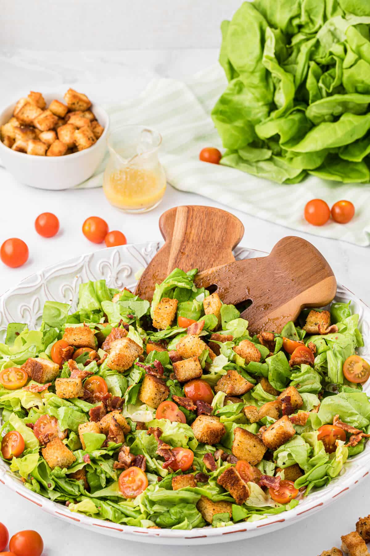 BLT Salad in a white bowl with wooden salad tongs.