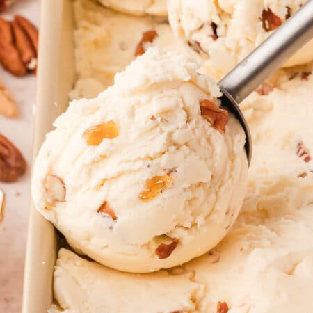 Maple pecan ice cream in a container with an ice cream scoop.