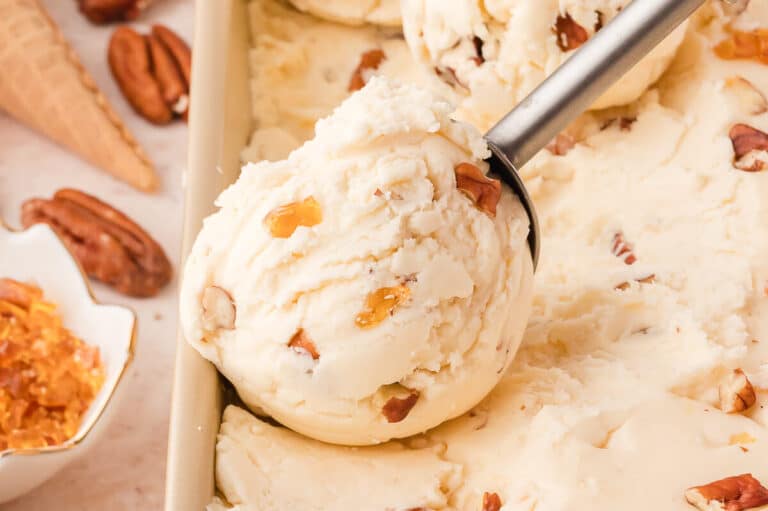 Maple pecan ice cream in a container with an ice cream scoop.