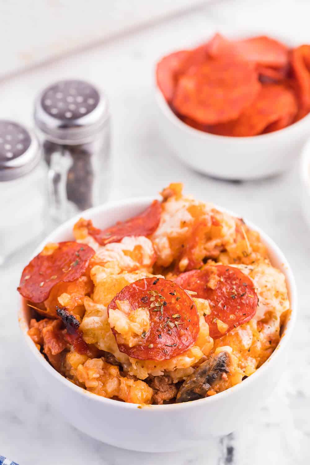 Pizza tater tot casserole served in a white bowl.