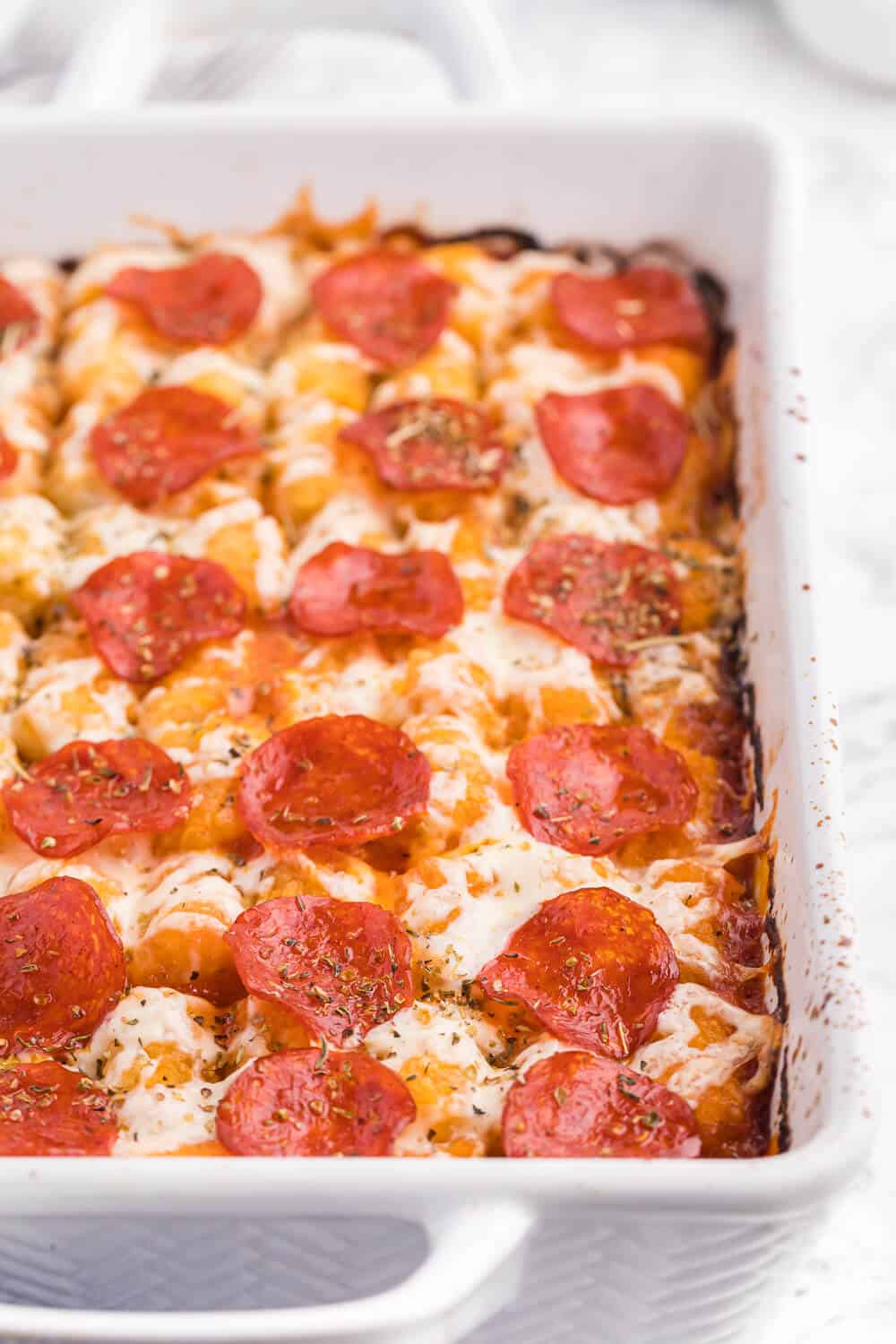 Pizza tater tot casserole in a white casserole dish.