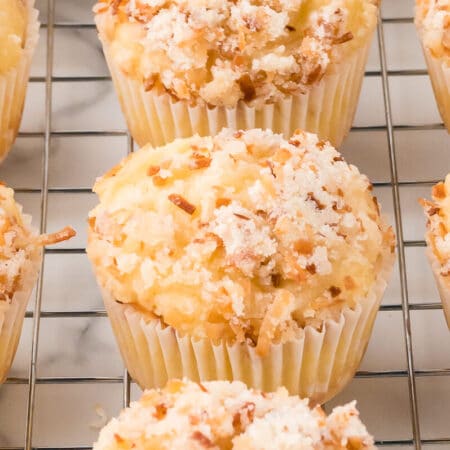 Toasted coconut muffins on a wire rack.