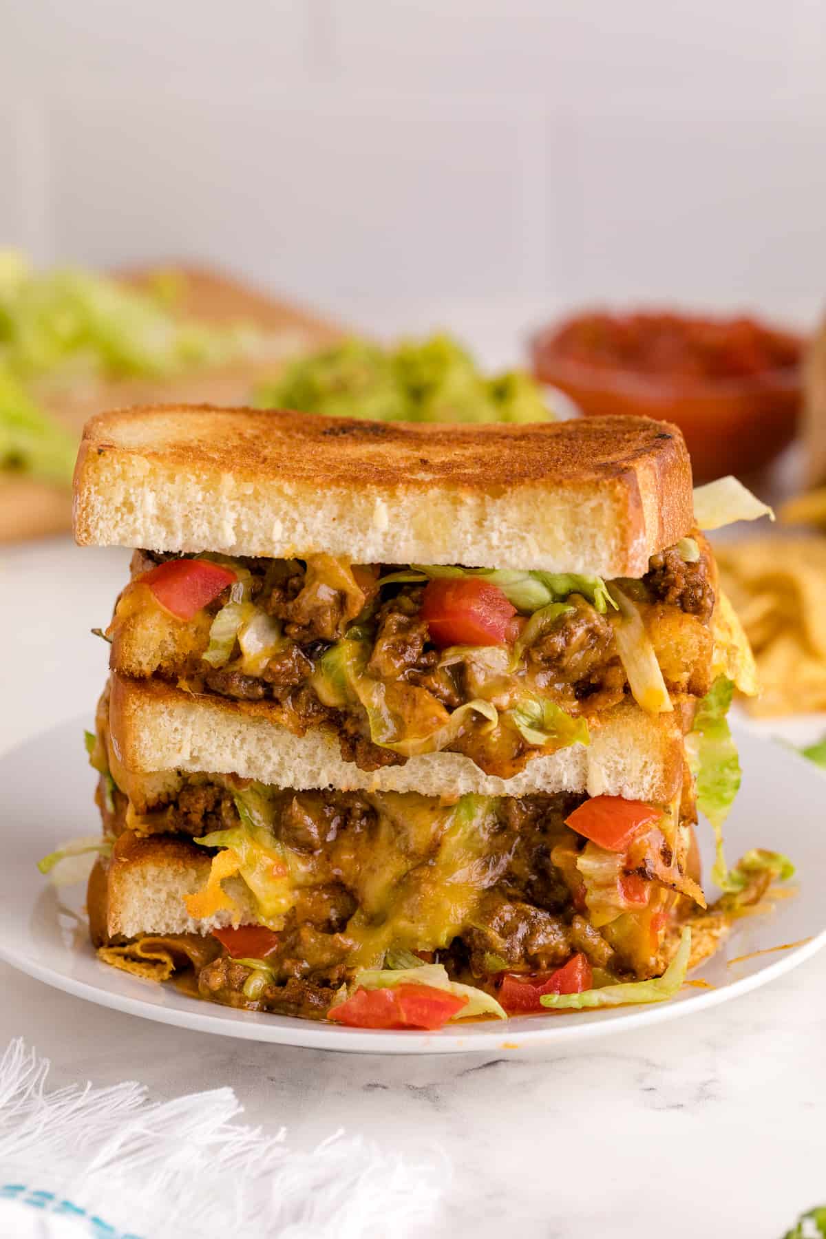 Taco grilled cheese sandwich stacked on a plate.