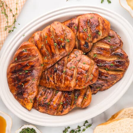 A group of chicken breasts on a white platter.