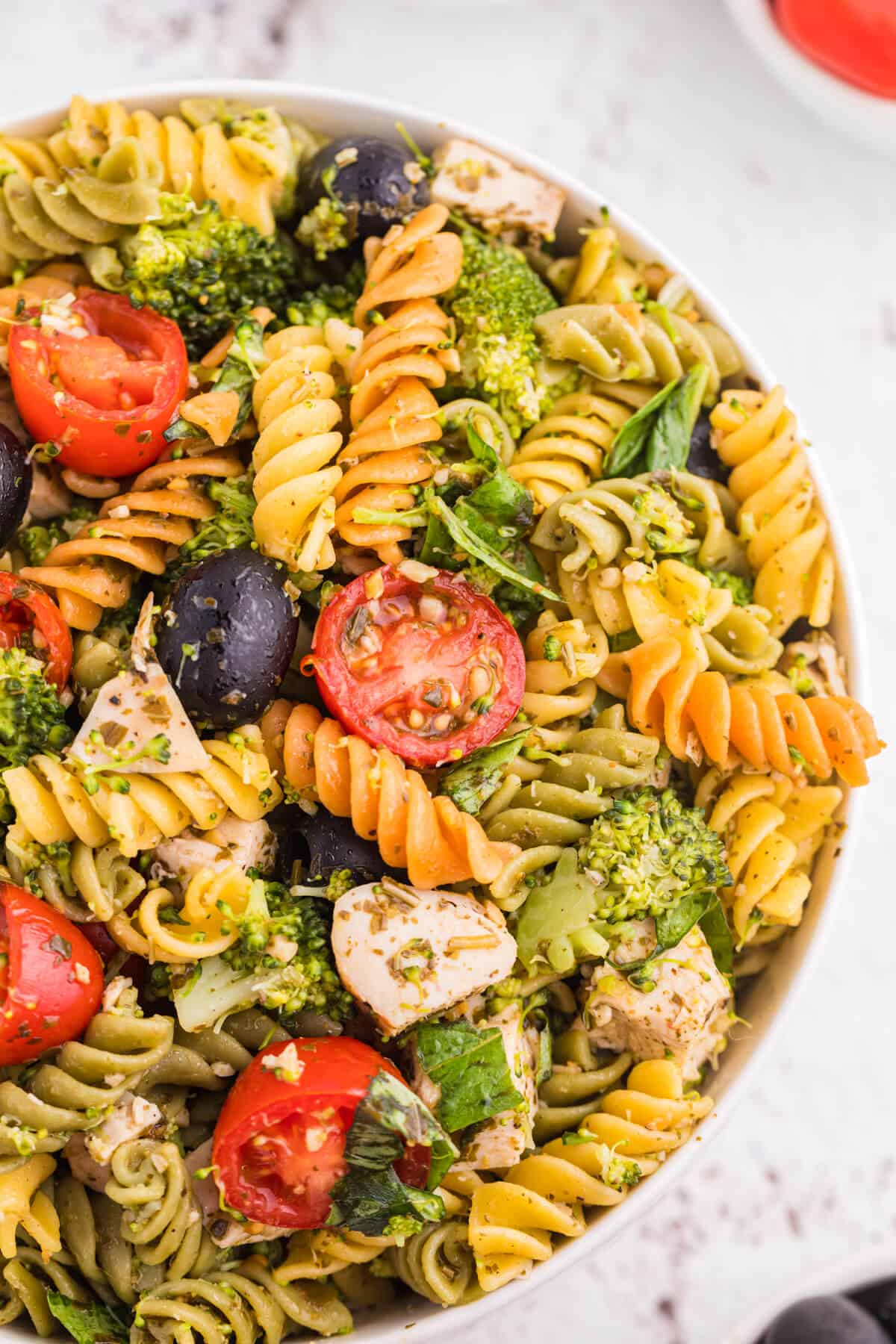 Pesto chicken pasta salad in a white bowl.