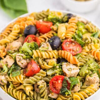 Pesto chicken pasta salad in a white bowl.