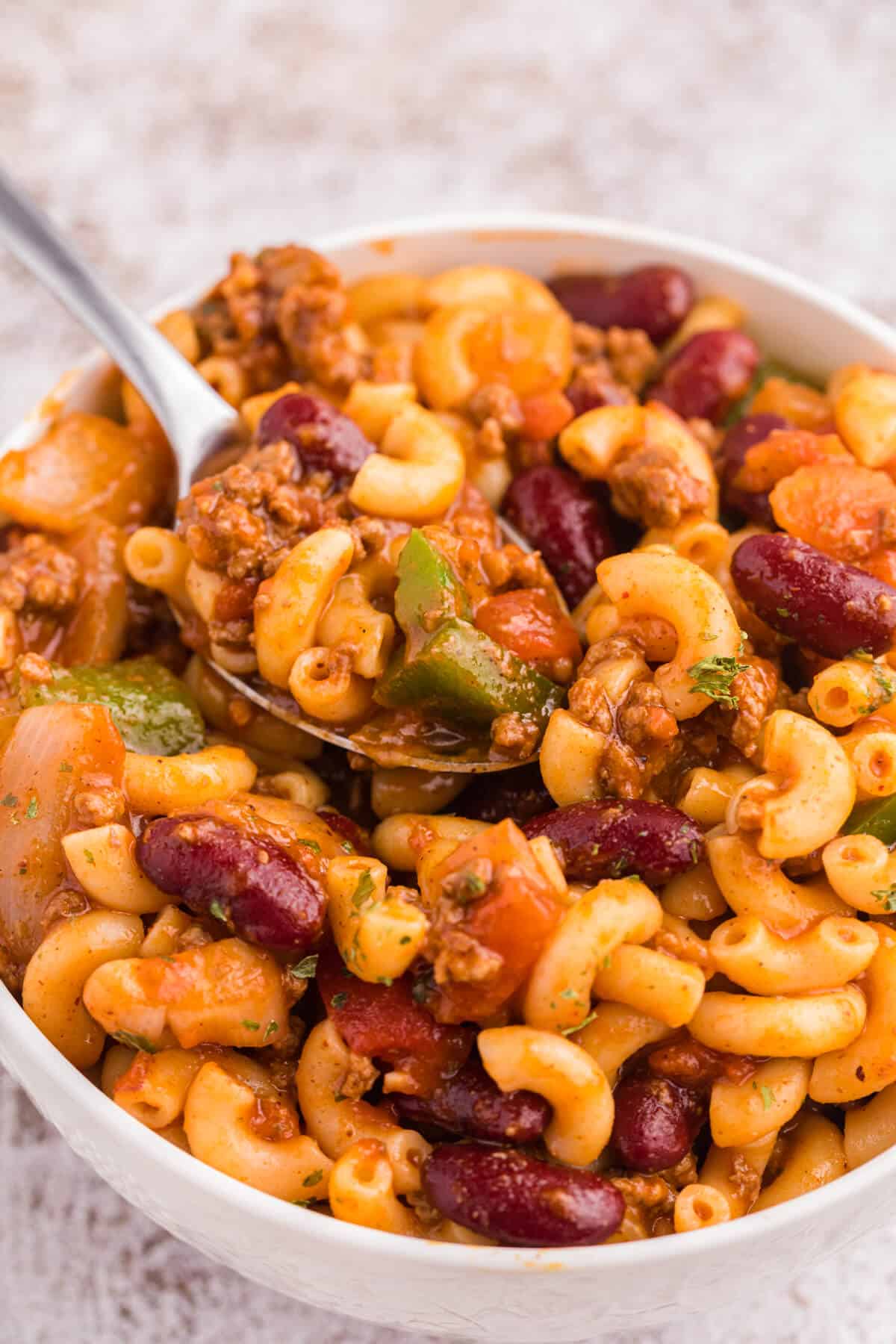 Chili macaroni in a white bowl with a spoon.