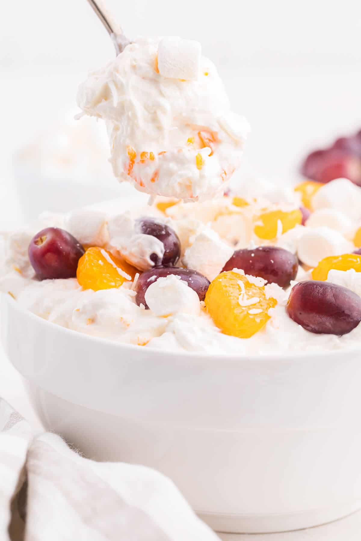 Creamy fruit salad on a serving spoon.