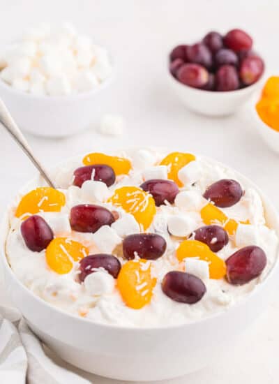 Creamy fruit salad in a bowl with a spoon.