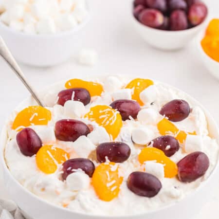 Creamy fruit salad in a bowl with a spoon.