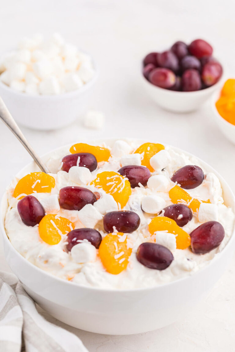 Creamy fruit salad in a bowl with a spoon.