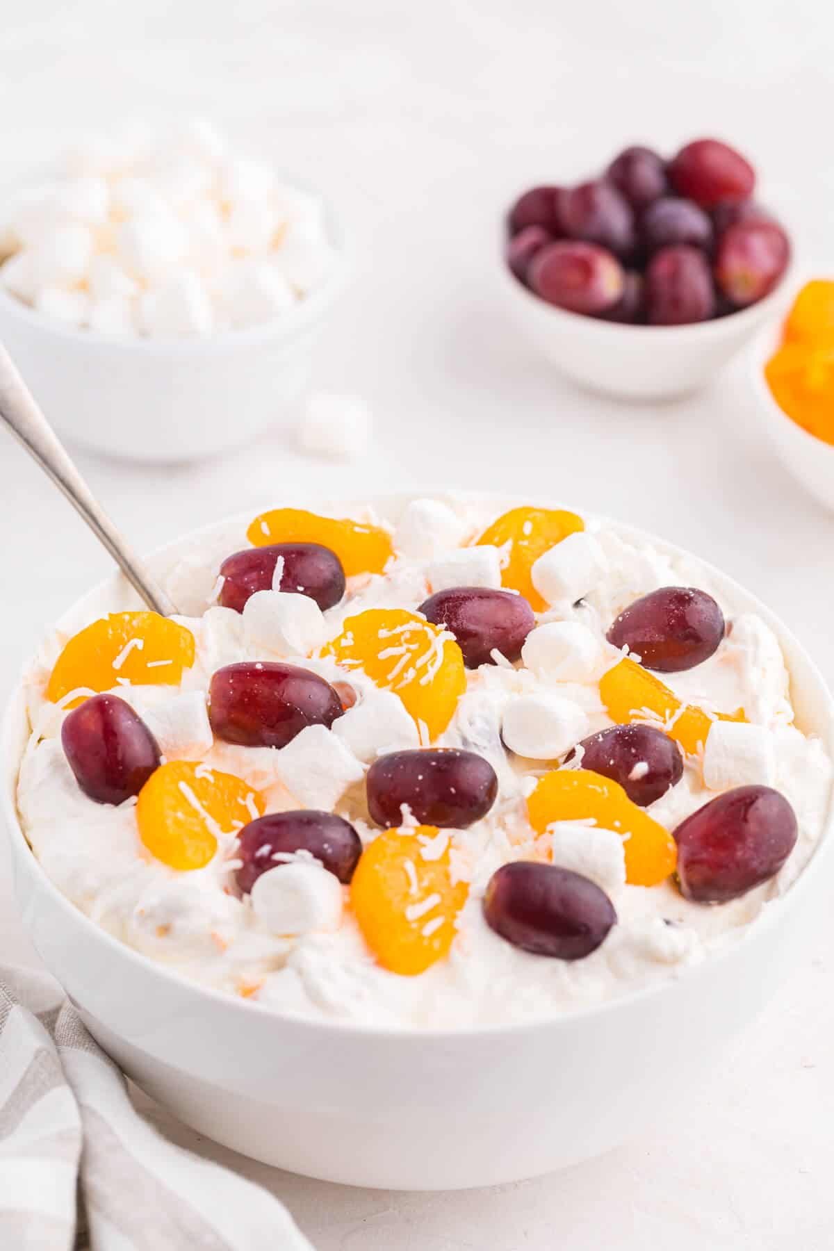 Creamy fruit salad in a bowl with a spoon.