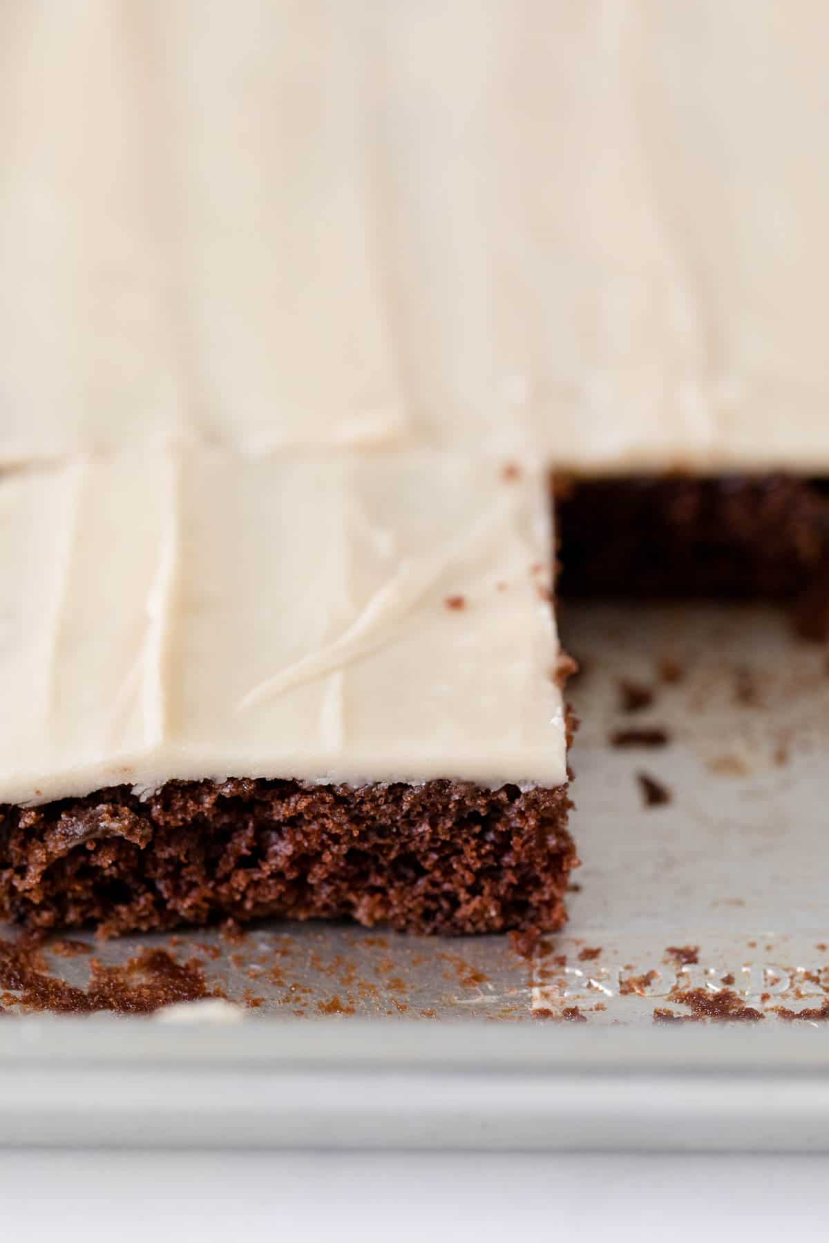 root beer float sheet cake in a pan with a few pieces cut out