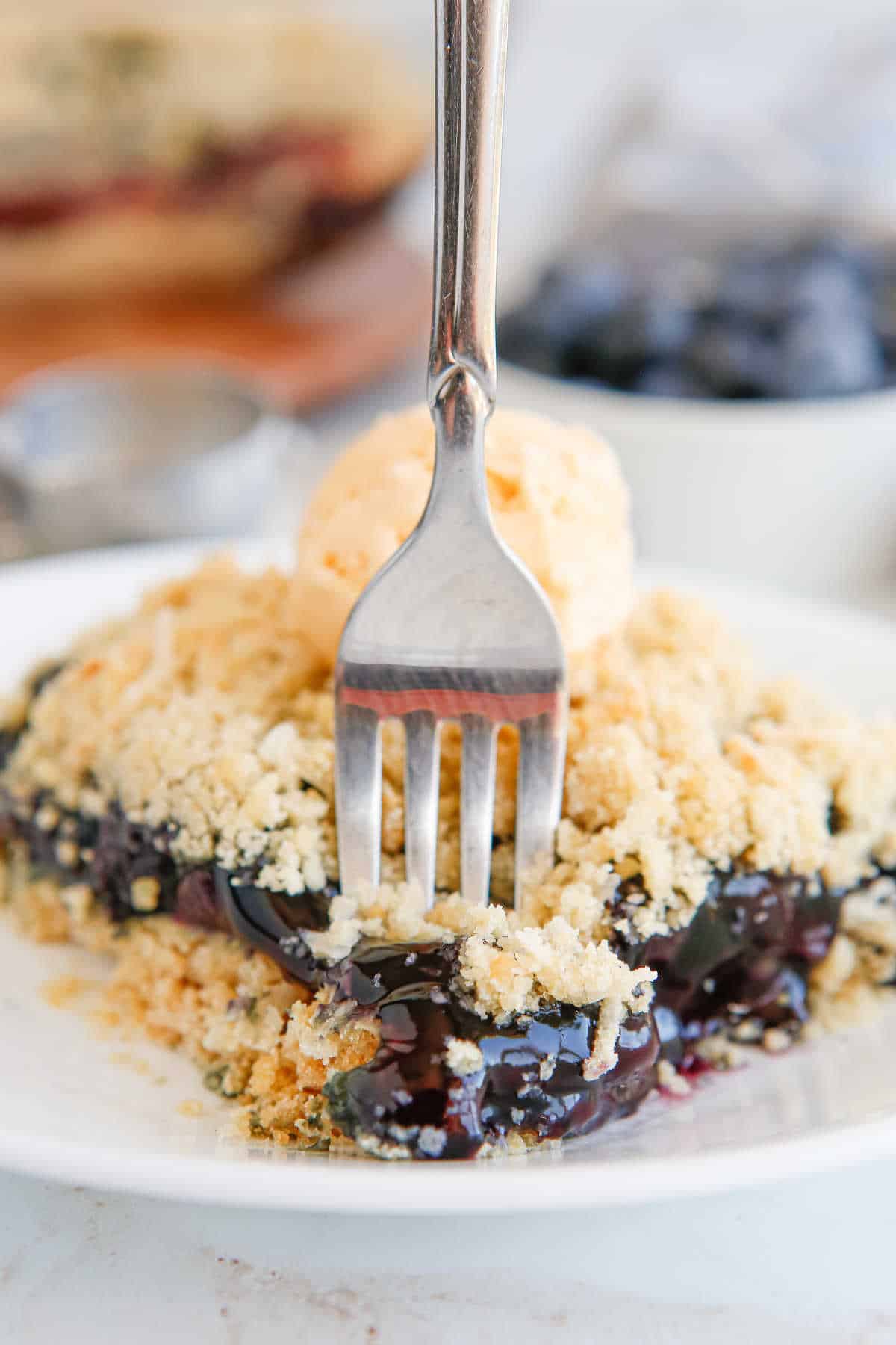 Blueberry crackle cake piece on a plate with a fork in it.