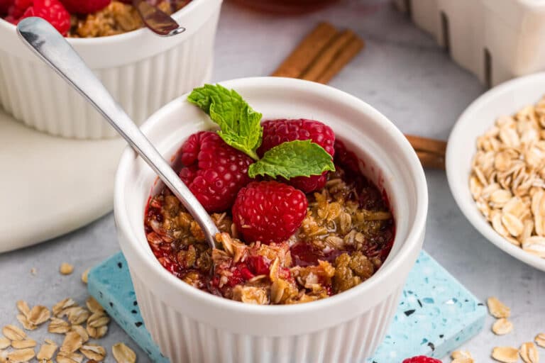 Raspberry crisp in a white ramekin with a spoon.