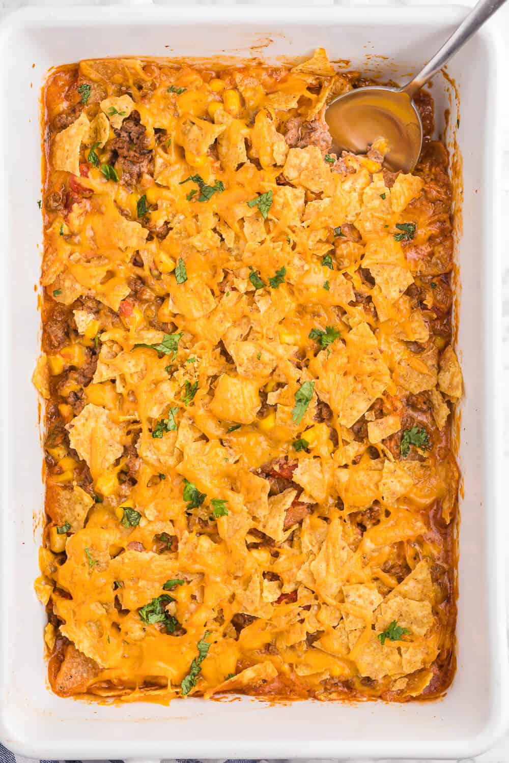 Beef Nacho Bake - This beefy nacho casserole is a welcome change from the traditional Taco Night. It hits all the right notes with cheese, beef, salsa and crunchy tortilla chips.