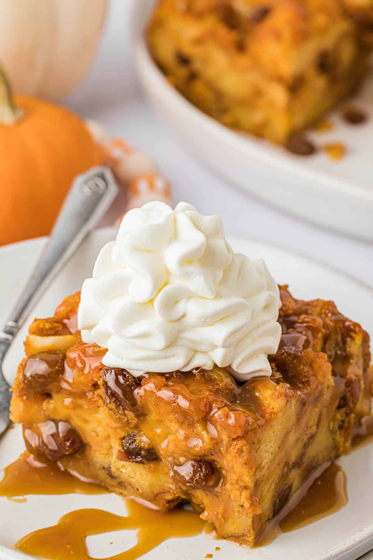 A piece of pumpkin bread pudding topped with whipped cream.