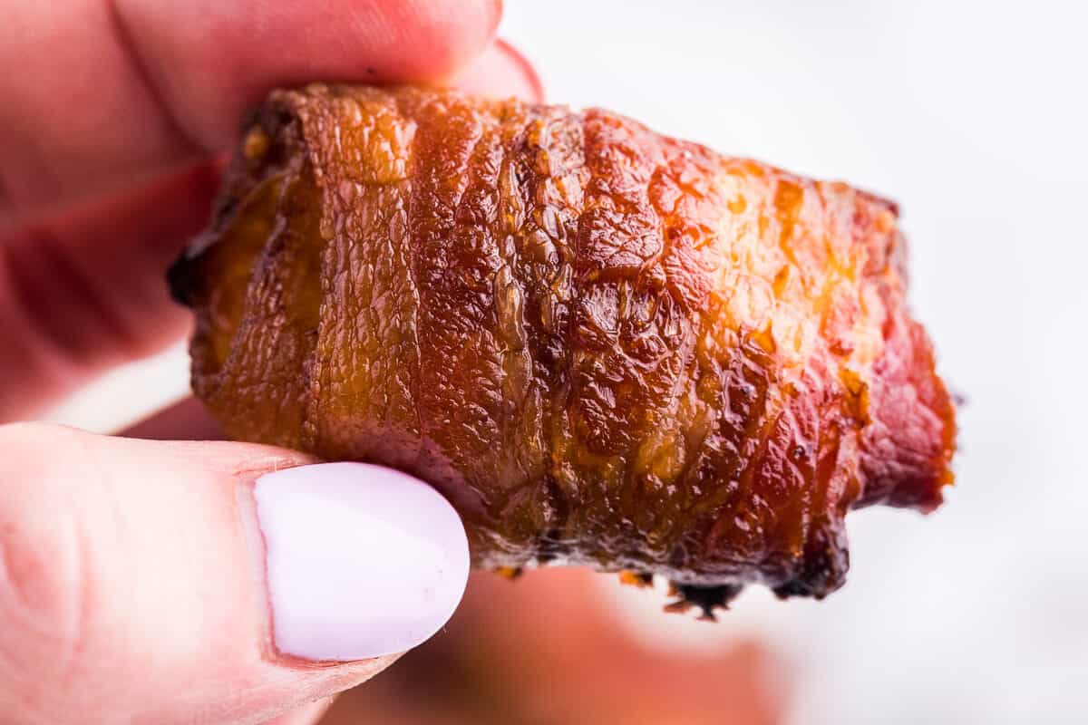 An hand holding a stuffed bacon roll.