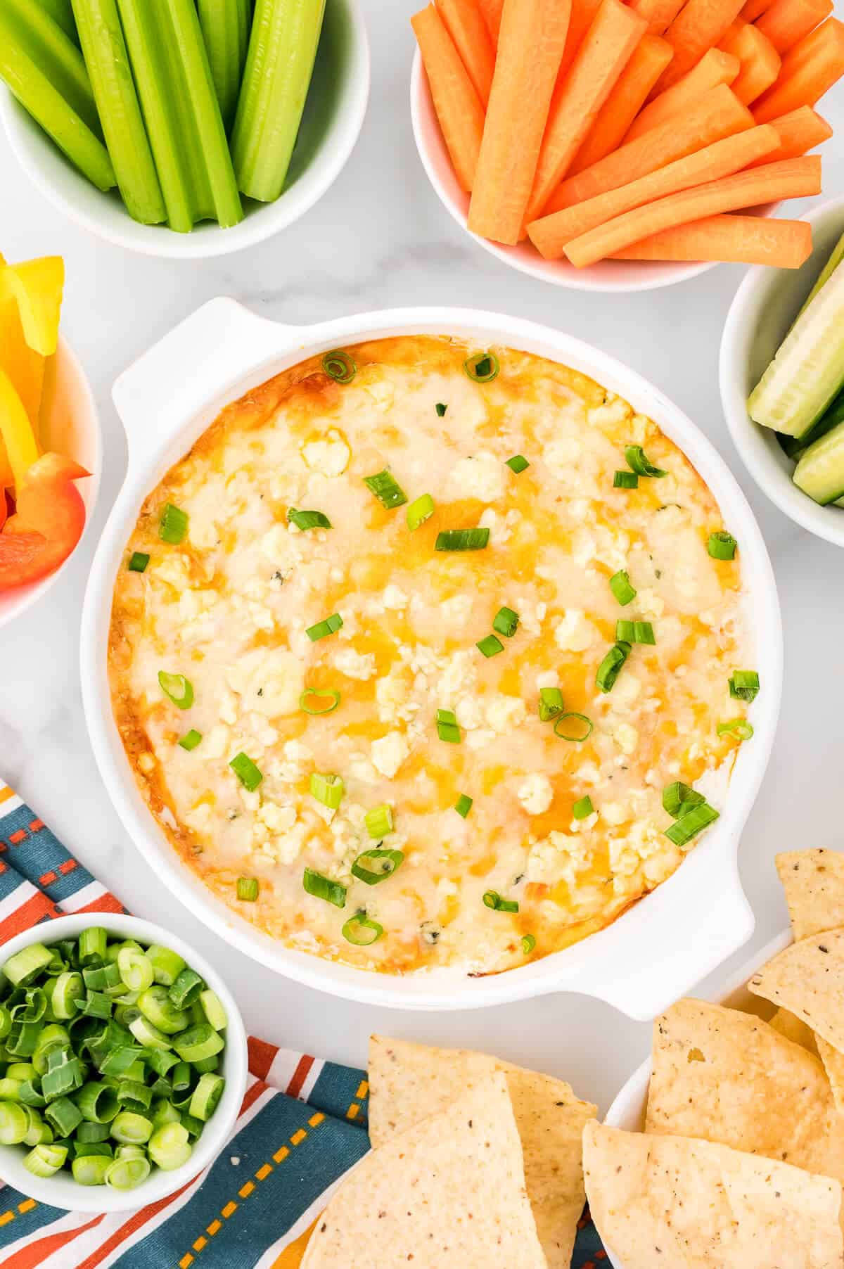 Buffalo chicken dip surrounded by veggies and tortilla chips.