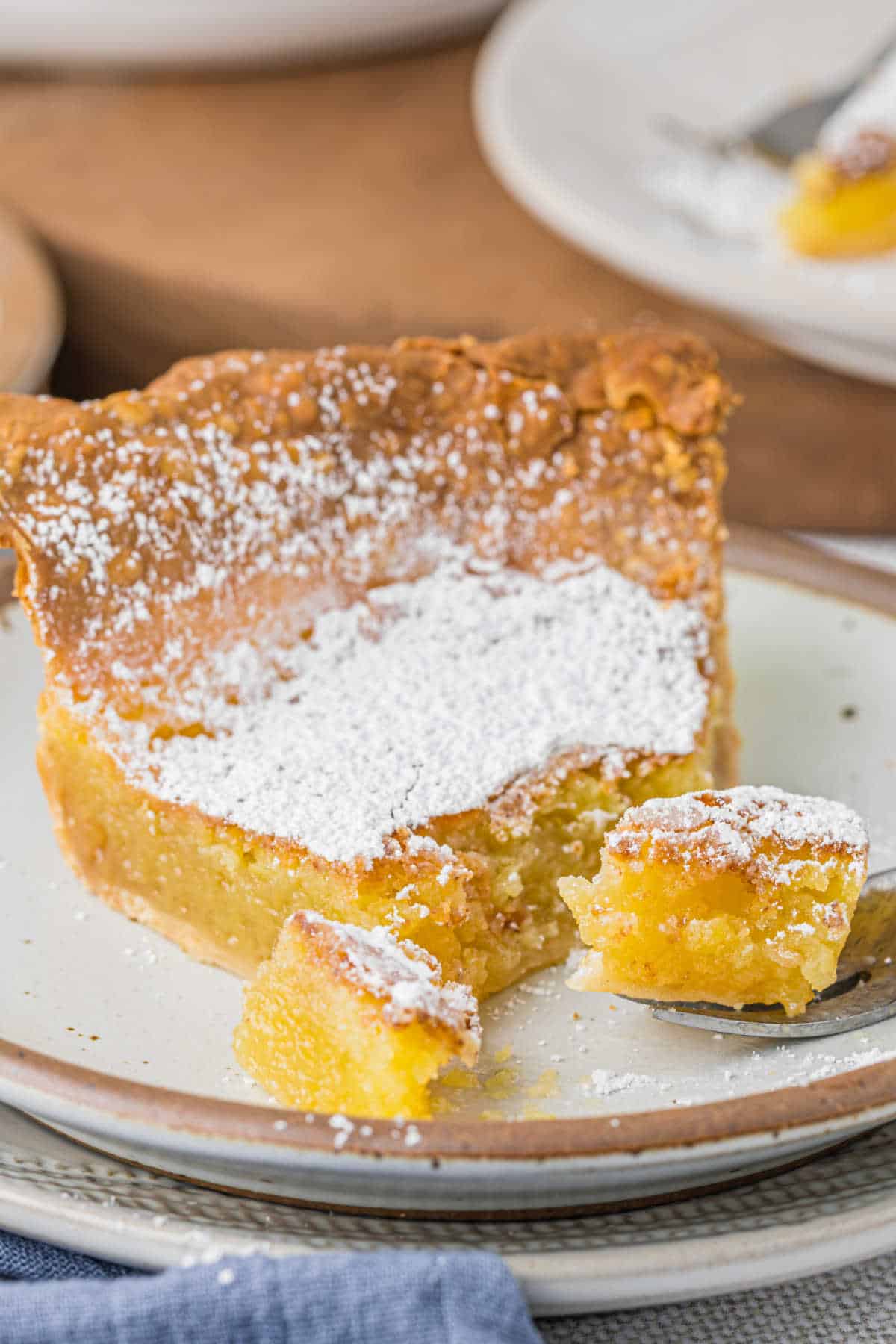 A slice of chess pie on a plate with a piece cut off the end.