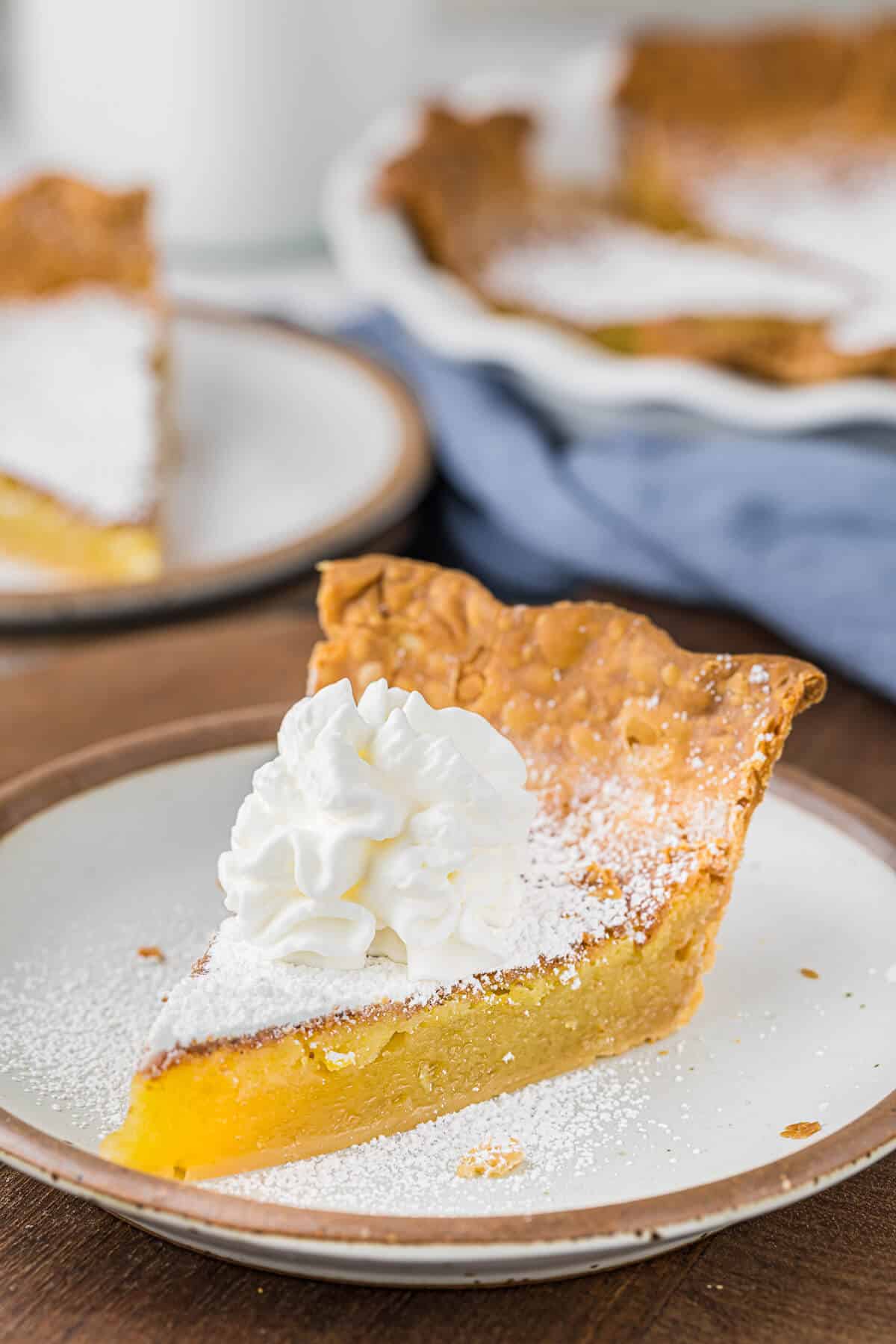 A slice of chess pie topped with whipped cream on a plate.